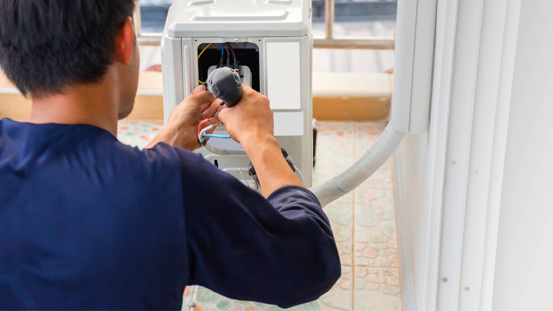 A man is fixing a washing machine with a screwdriver.