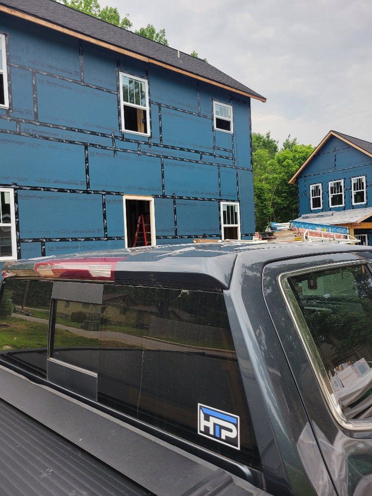 A black truck is parked in front of a blue building under construction.