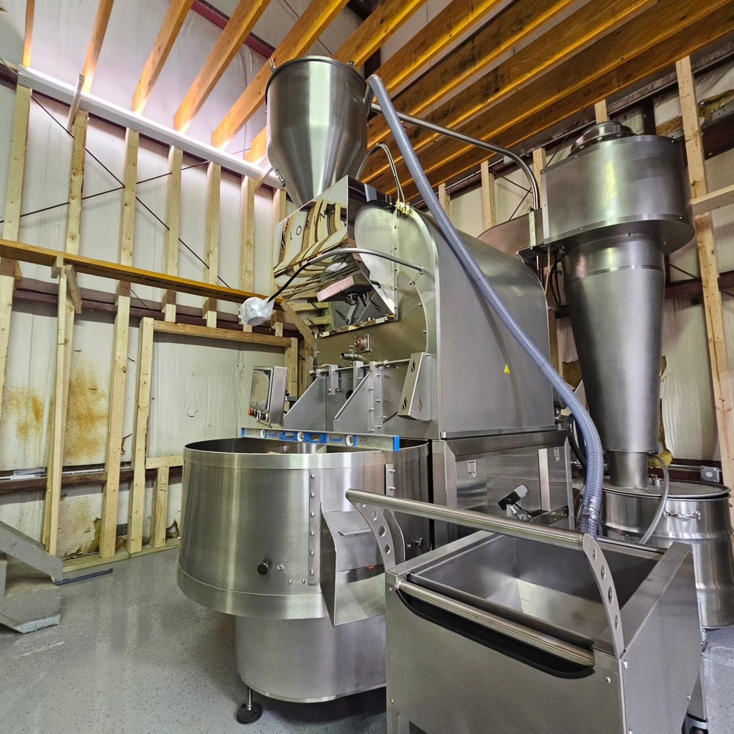 A large stainless steel machine in a room with wooden beams