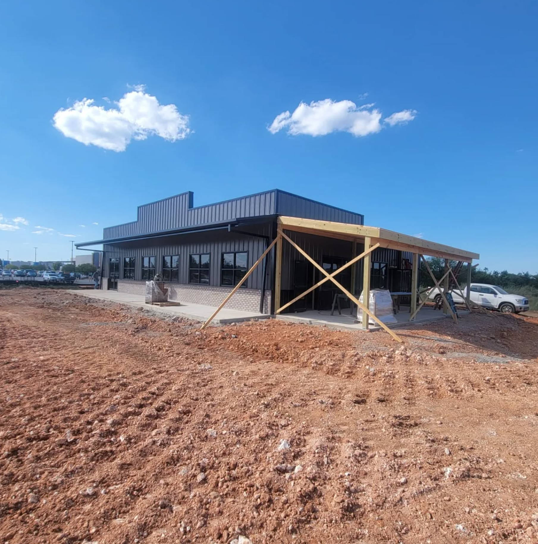 A building is being built in the middle of a dirt field.