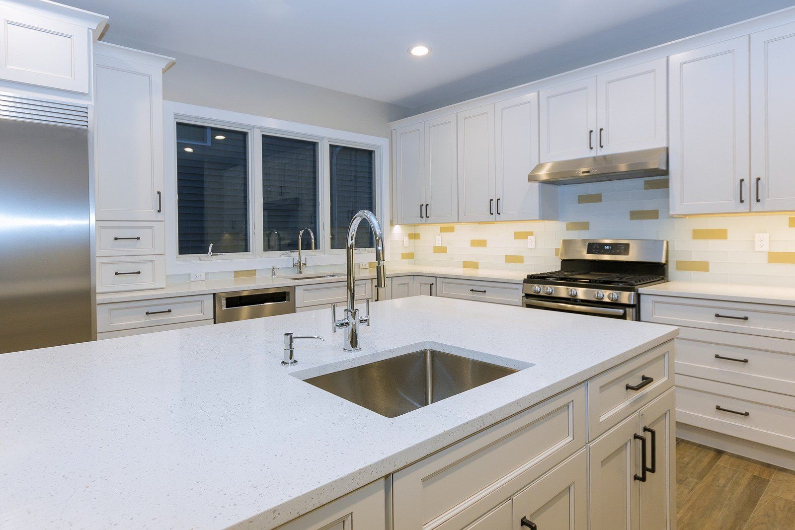 A kitchen with white cabinets , stainless steel appliances , and a large sink.