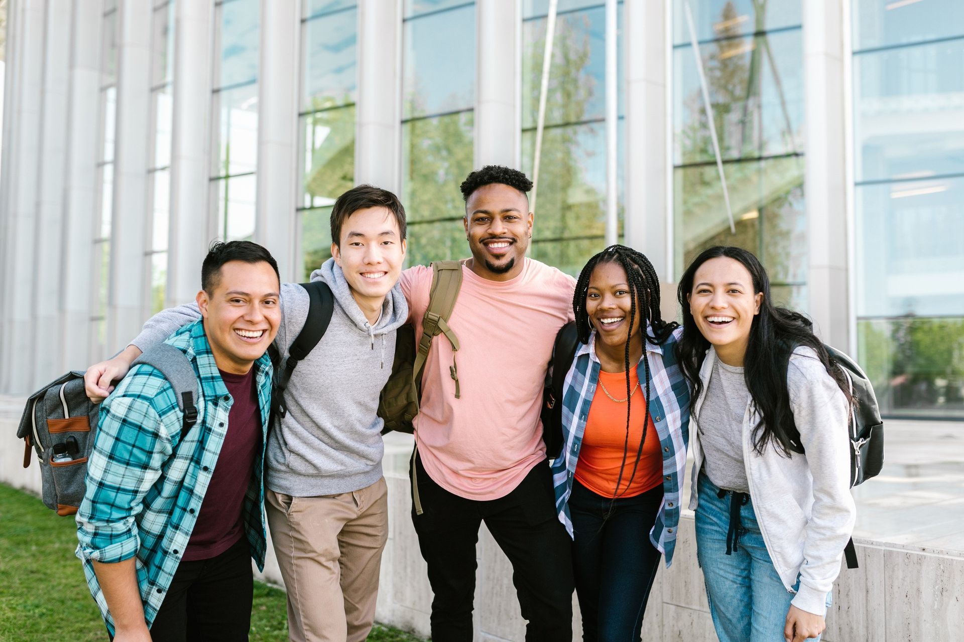 A group of young people are posing for a picture in front of a building.