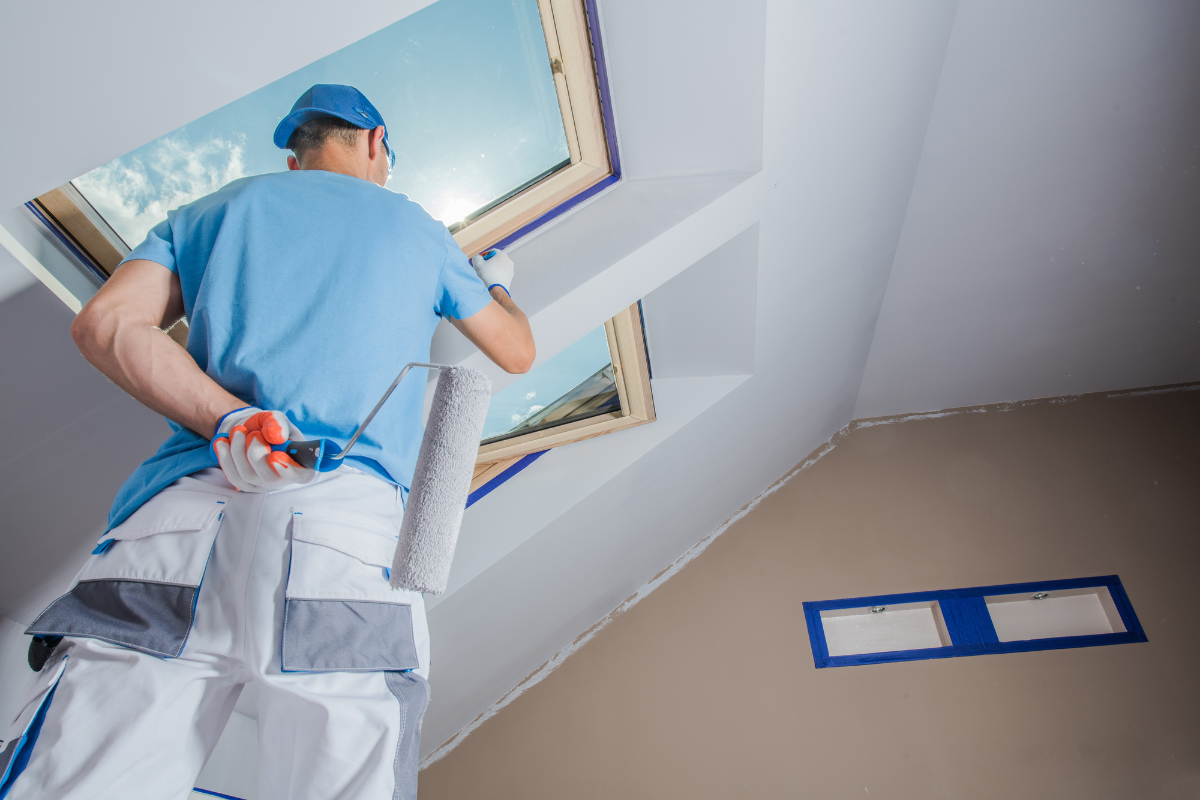 A man is standing on a ladder painting a room.