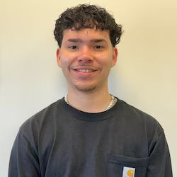 Jassiel Caraballo wearing a black carhartt shirt is smiling for the camera.