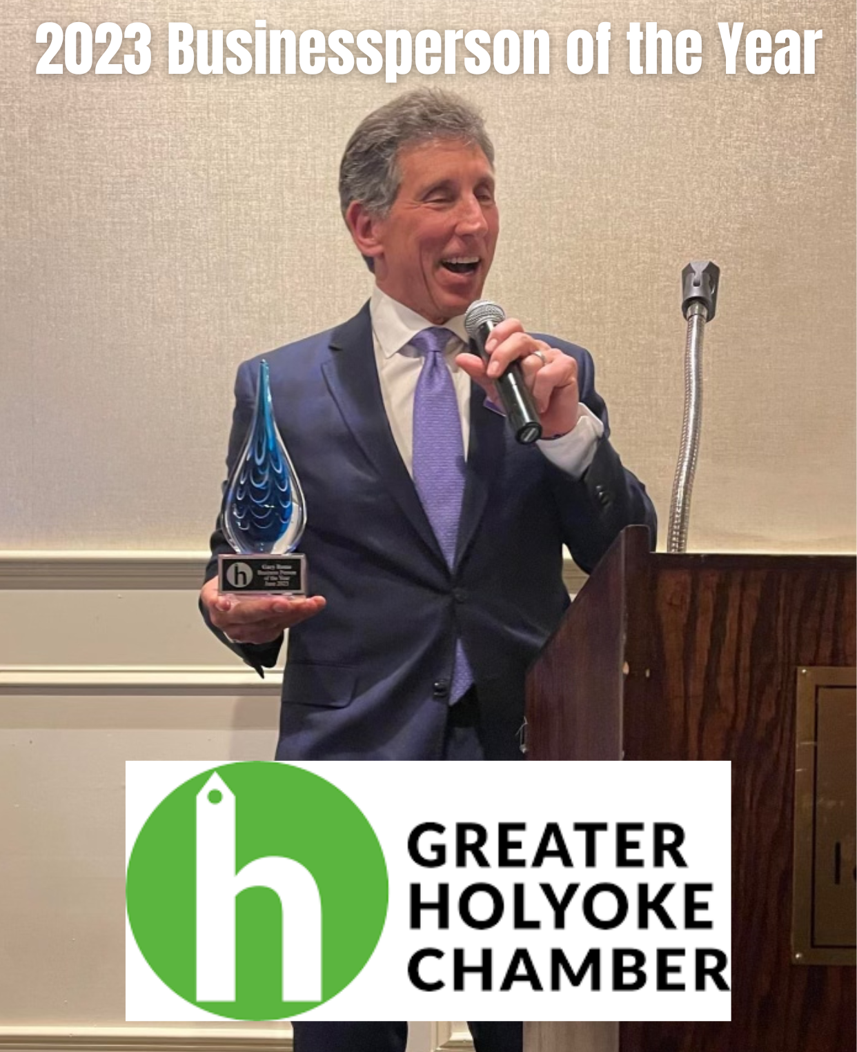 A man in a suit and tie is holding a trophy and speaking into a microphone ..