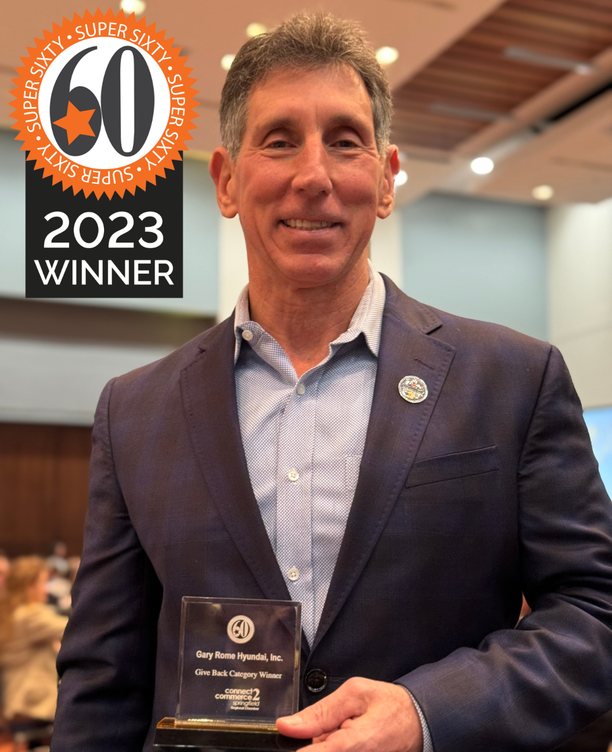 A man in a suit is holding a plaque that says 2023 winner