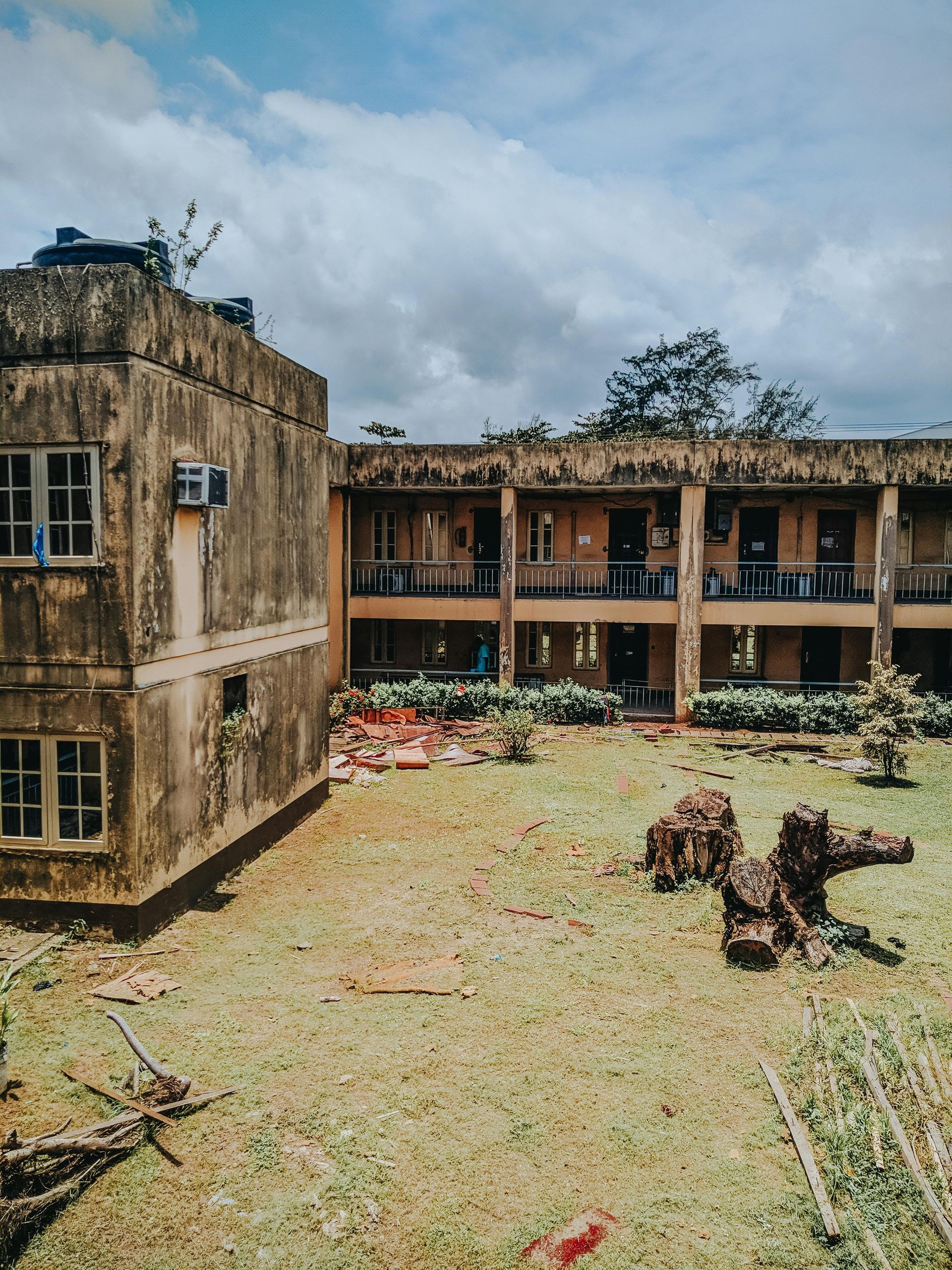 An old building with a lot of windows is sitting in the middle of a grassy field.
