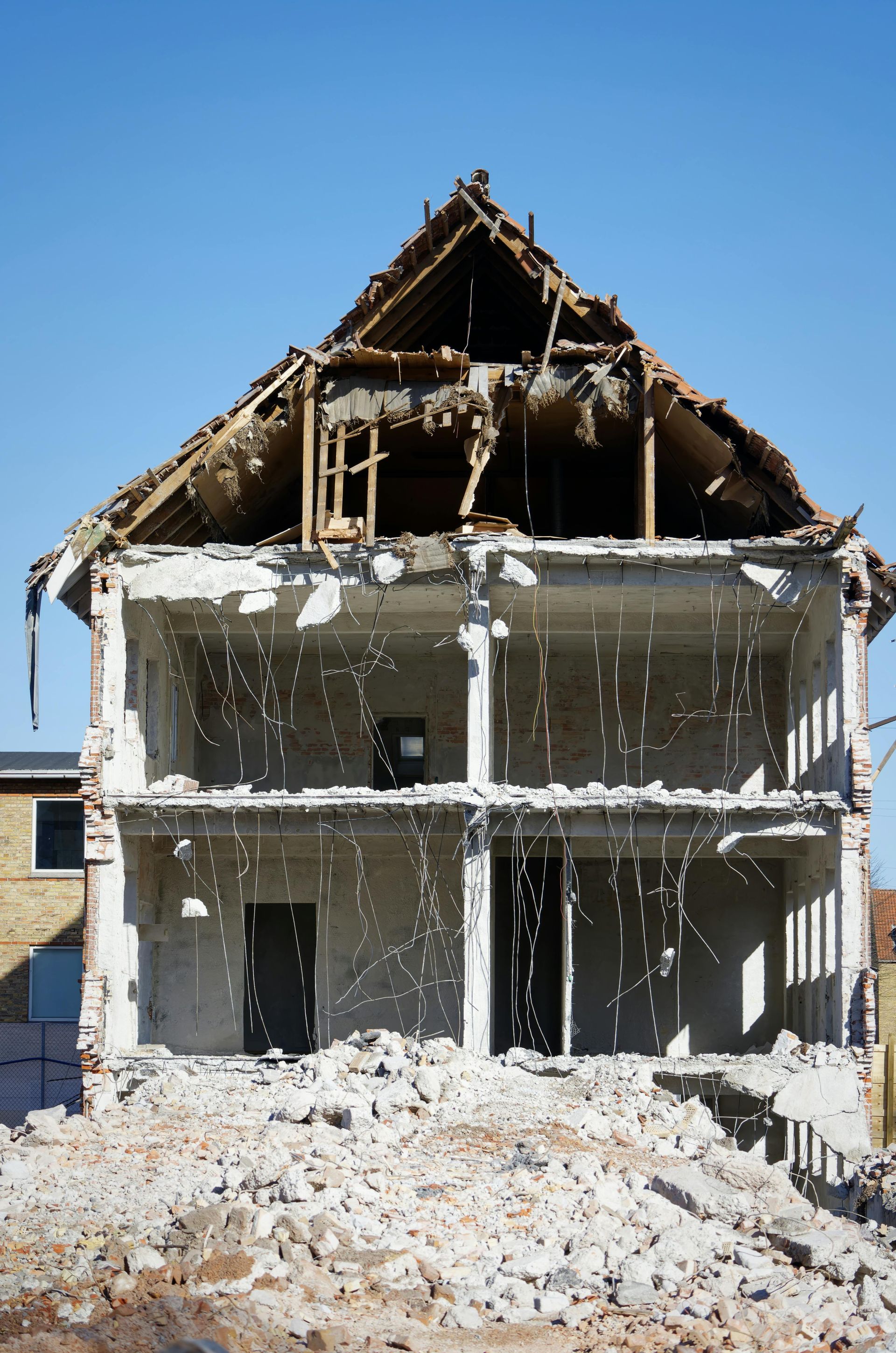 A large brick building is being demolished by a bulldozer