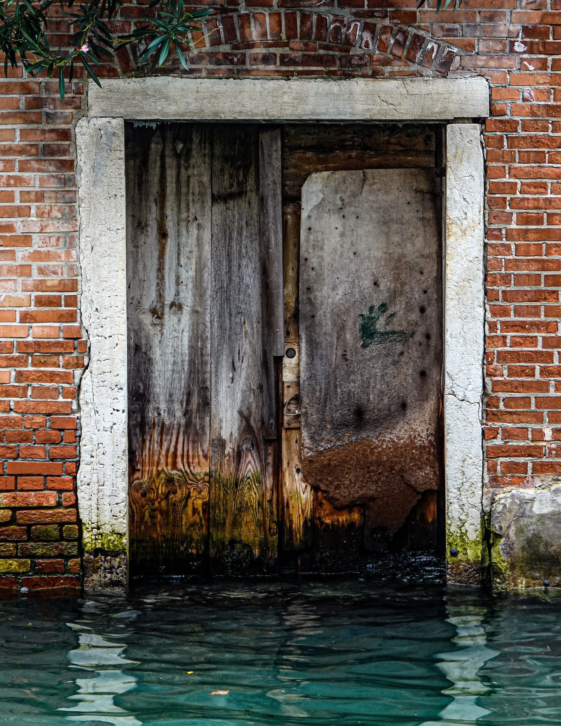 A brick wall with a wooden door surrounded by water