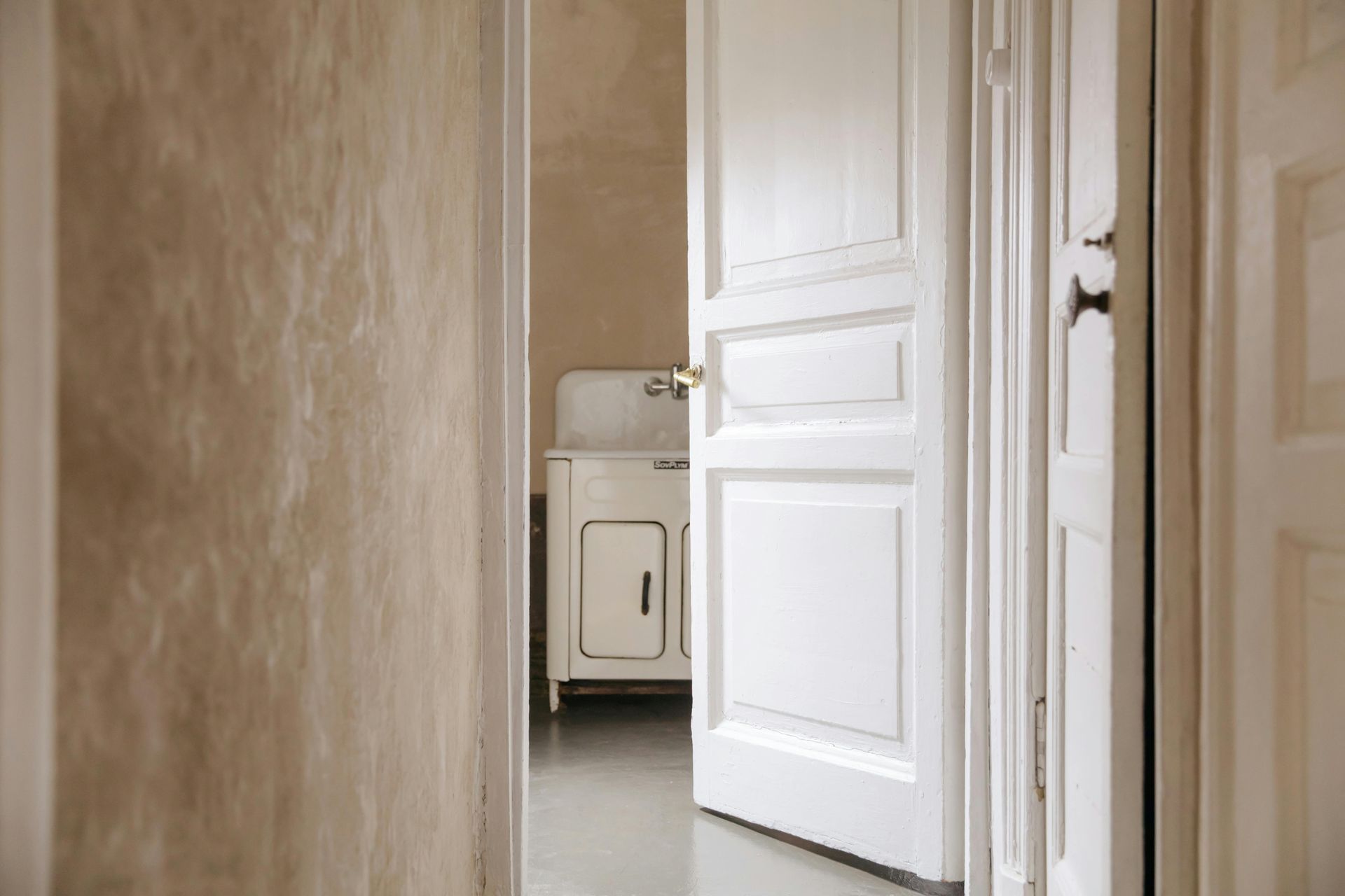 A white door is open to a bathroom with a sink.