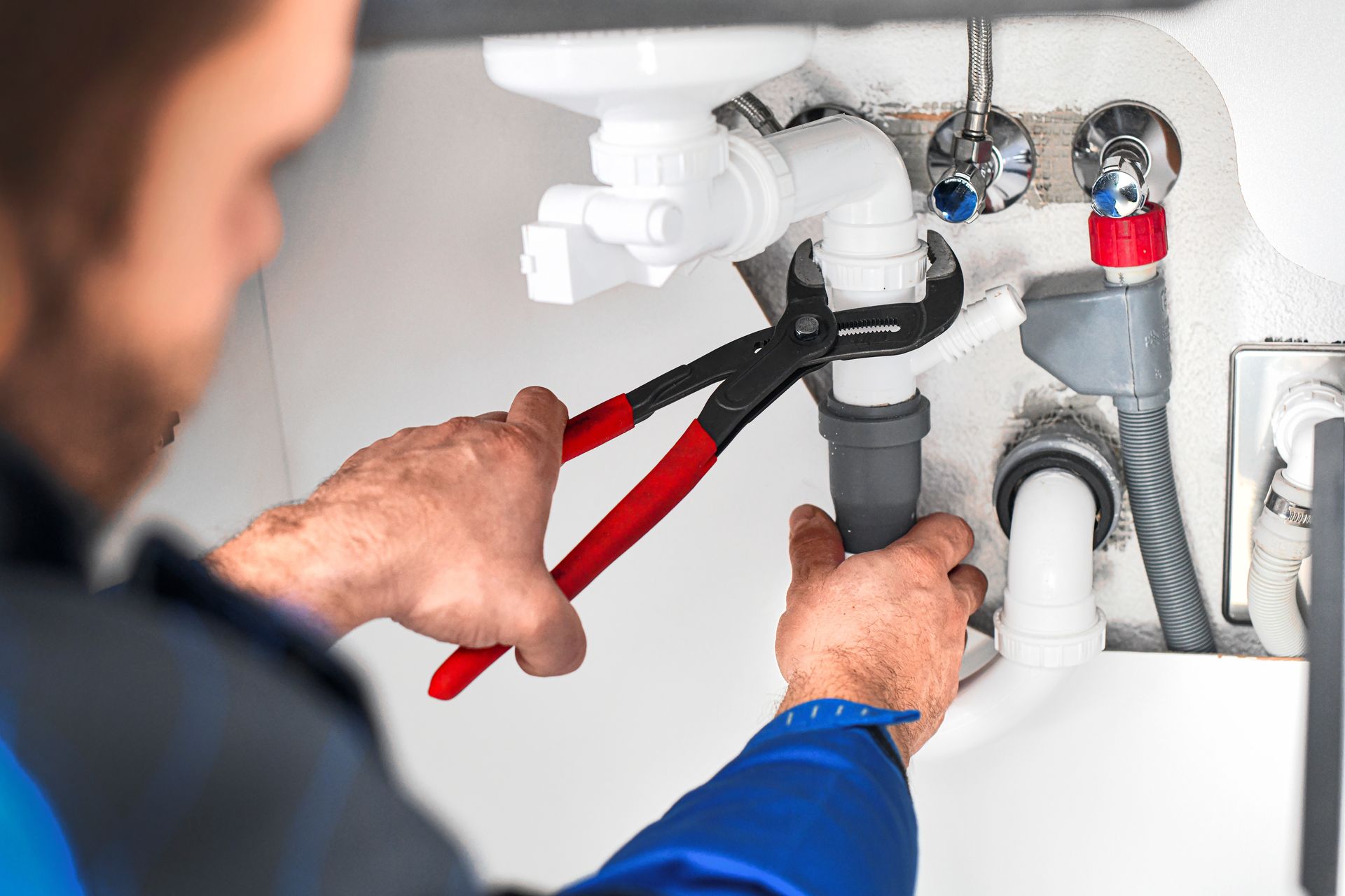 Plumber hands with wrench repair sink in bathroom.