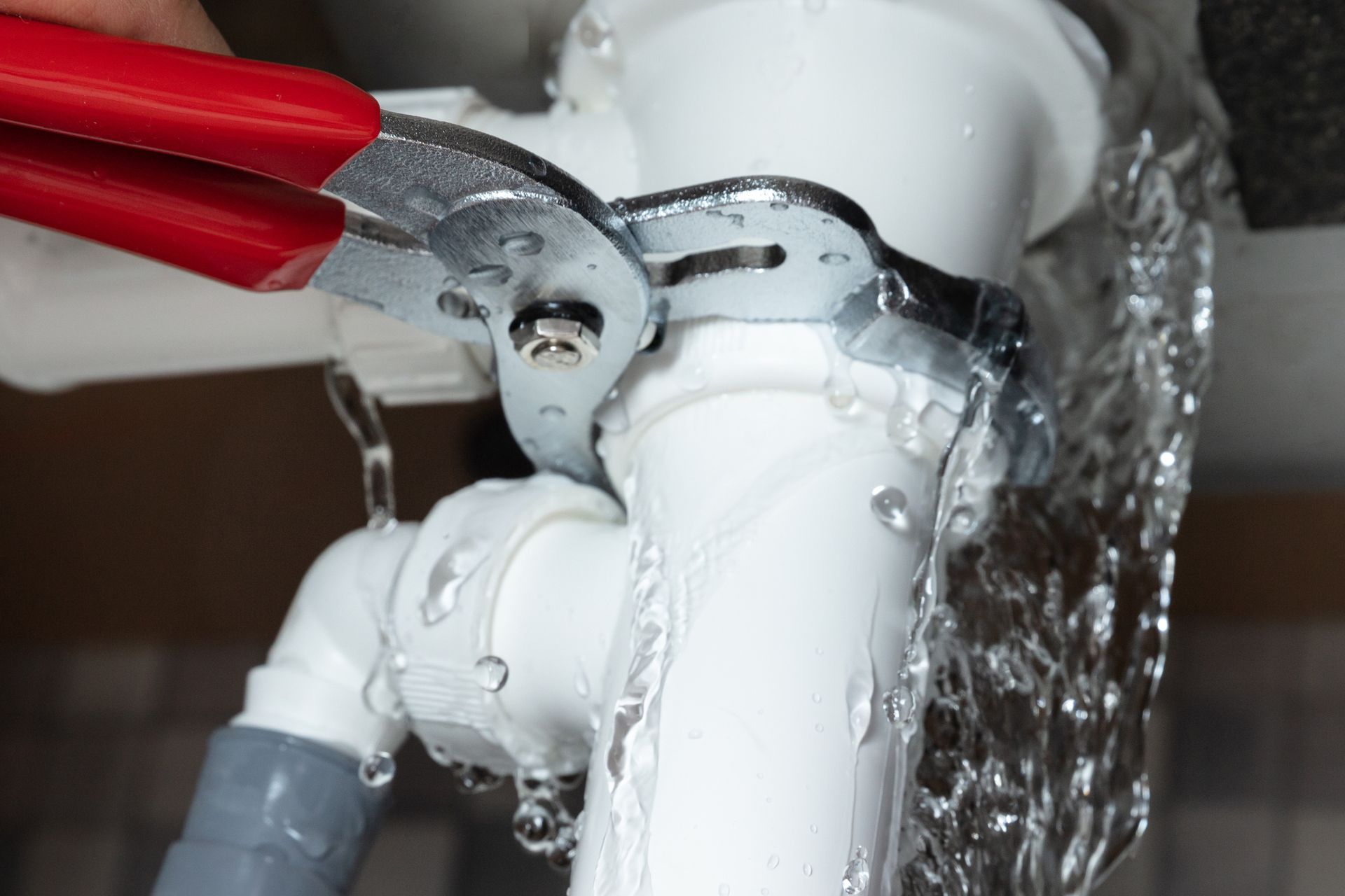 A person is fixing a leaking pipe with a wrench. — Elgin, IL — All Suburban Emergency Plumbing