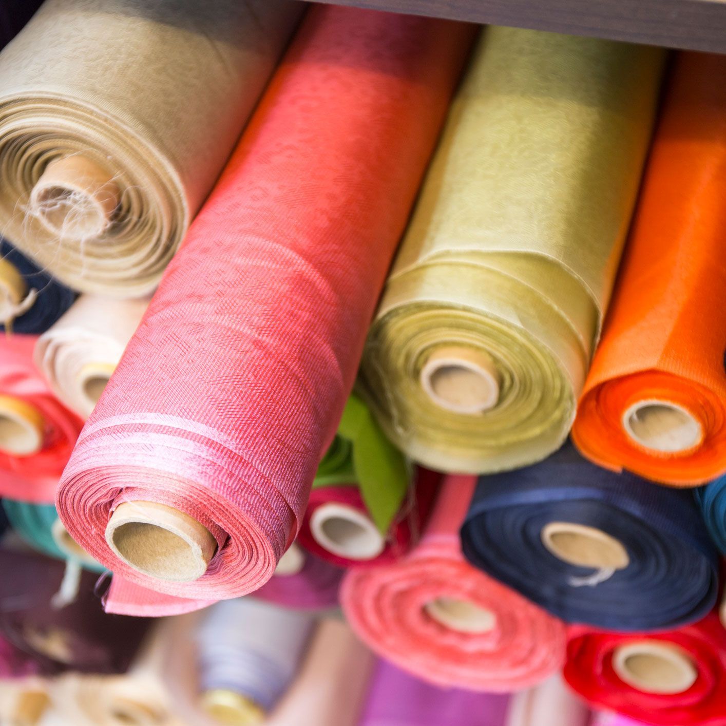 Colorful rolls of fabric stacked on shelves.