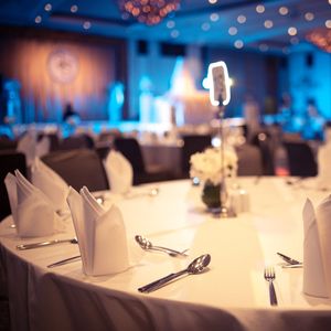 Round banquet table set for a formal event with white tablecloth and napkins.