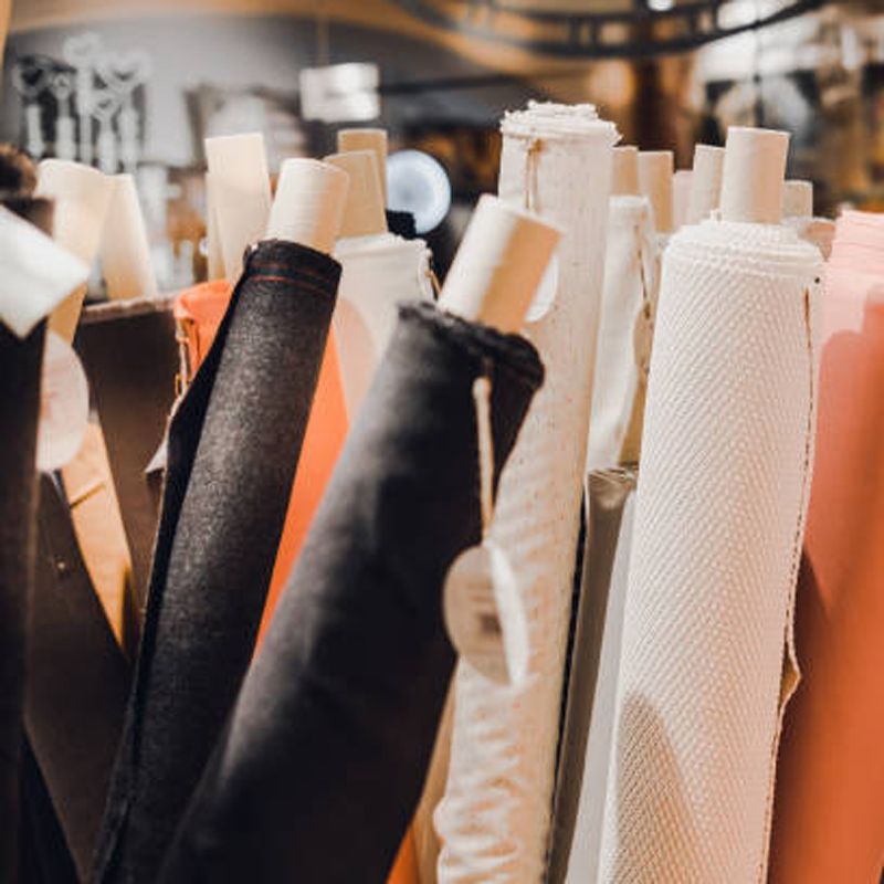 Fabric rolls of various colors in a store, including black, orange, and white.