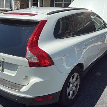 White Volvo SUV parked outside with hood open.