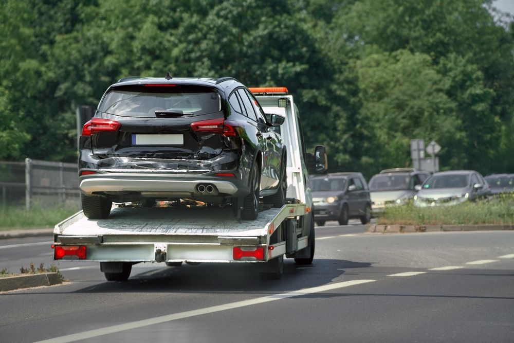 SUV on a tow truck, rear view on a road with other cars.