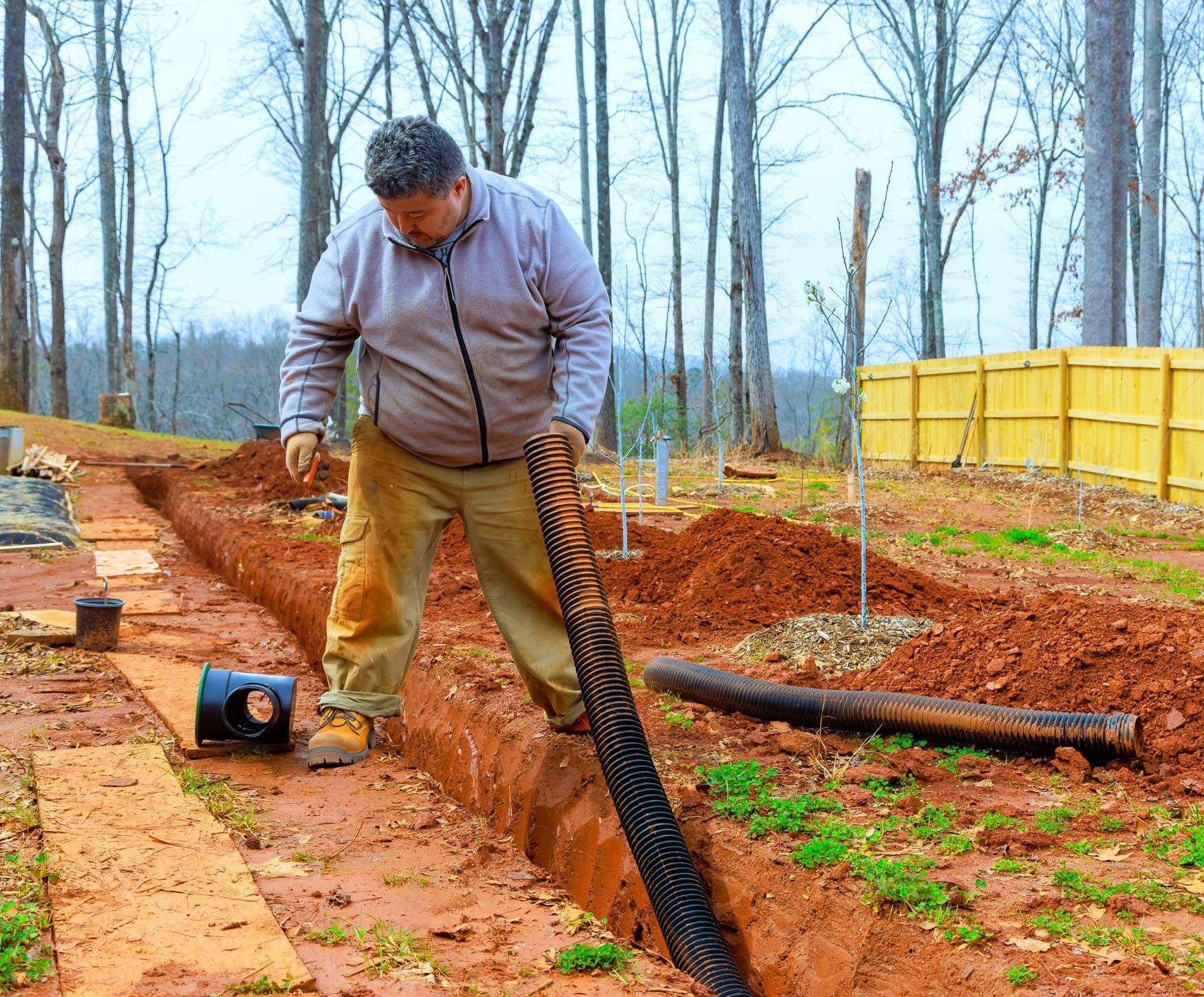 Worker works diligently to install drainage system in his backyard.