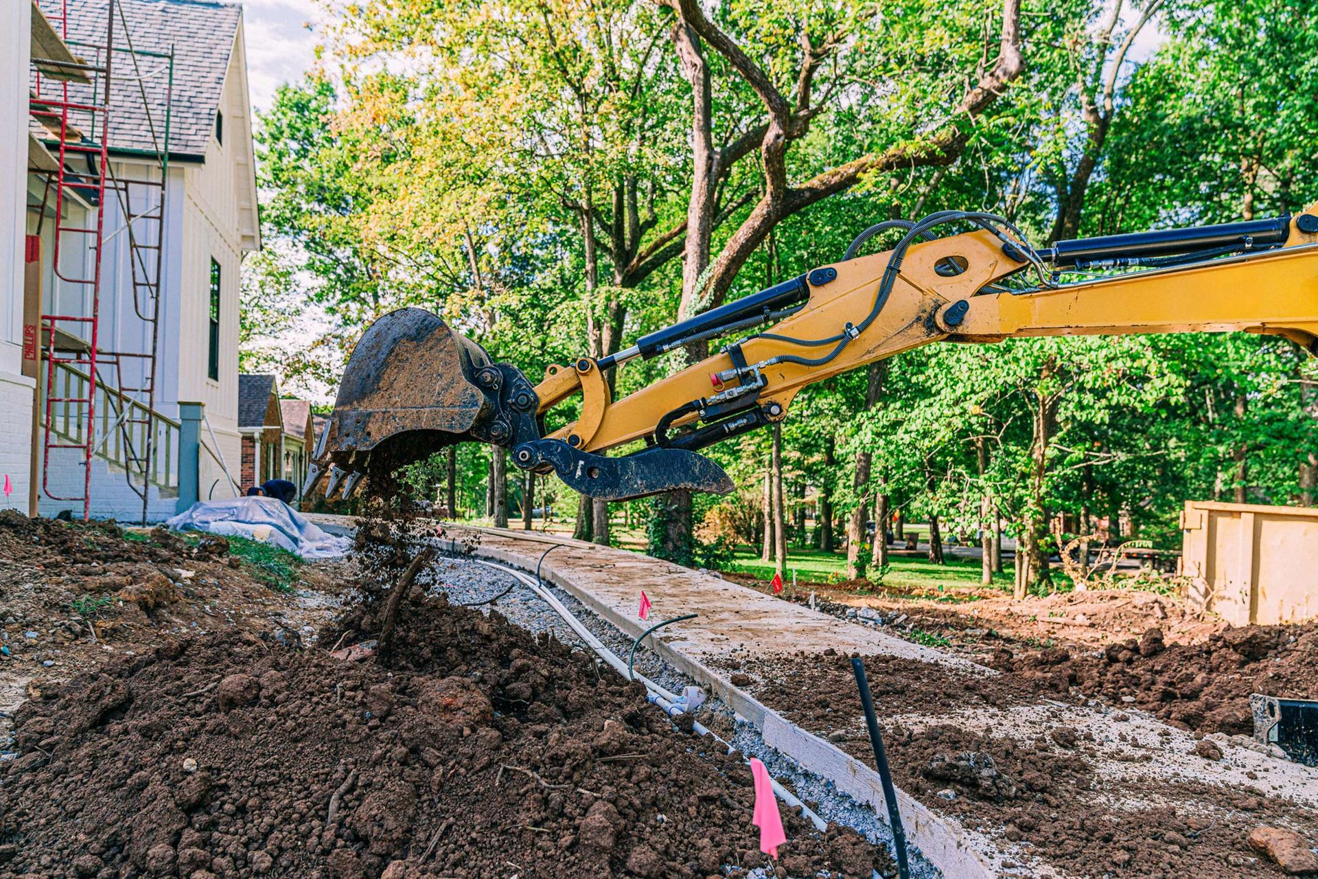 A yellow excavator is digging a hole in the ground at a construction site.
