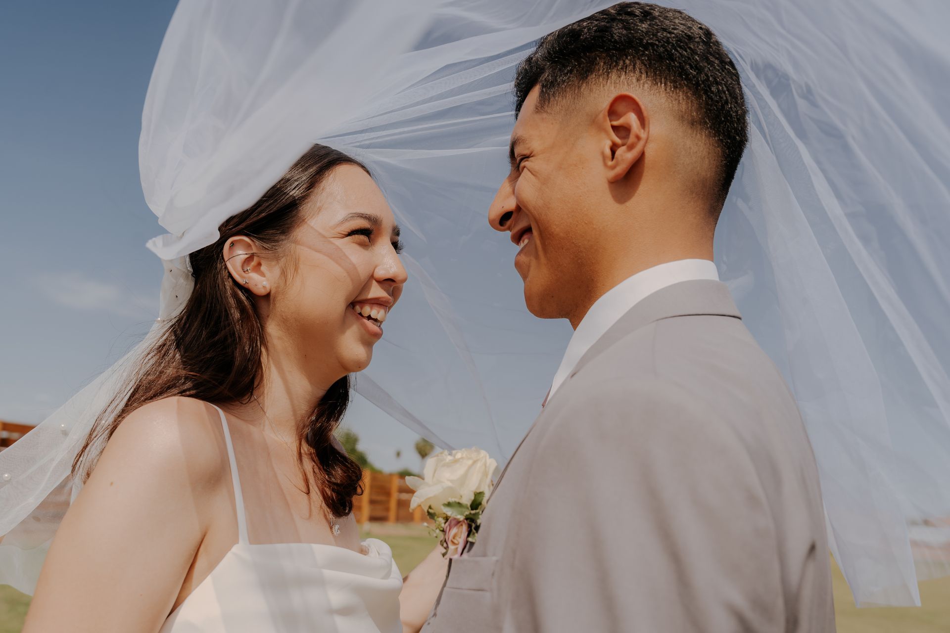 A bride and groom are kissing in front of the sun.