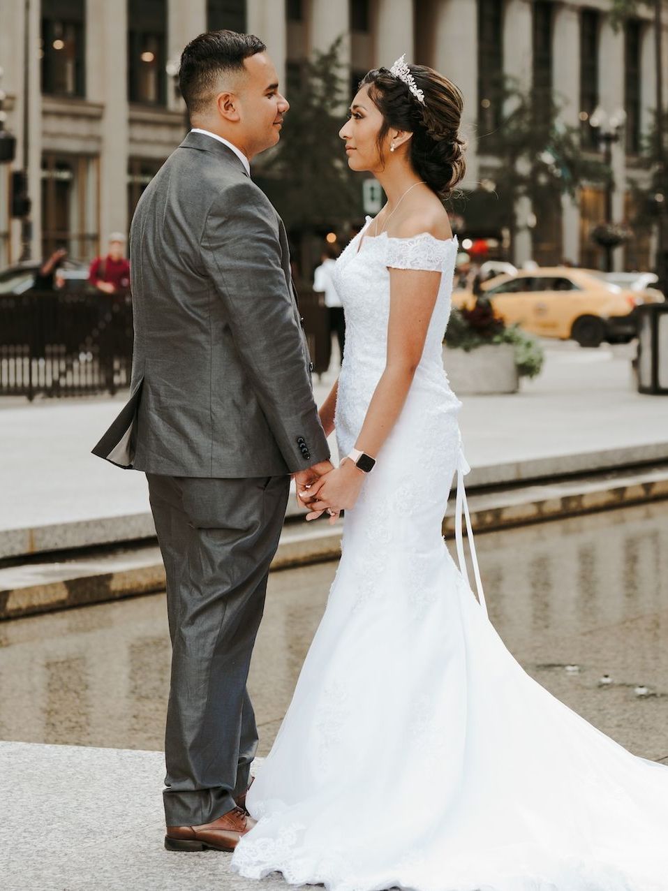 A bride and groom are holding hands and looking at each other.