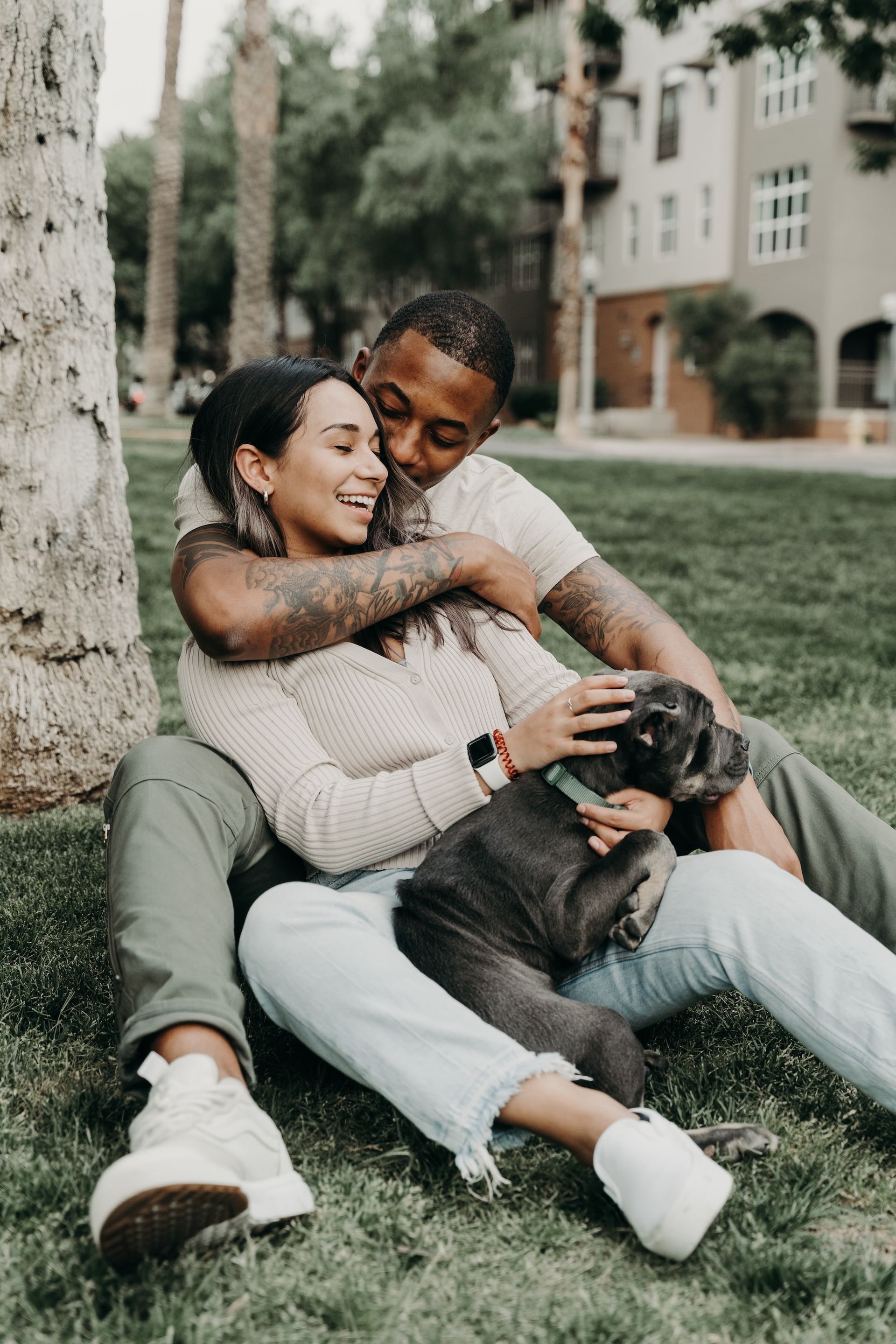 A man and a woman are sitting on the grass with a dog.