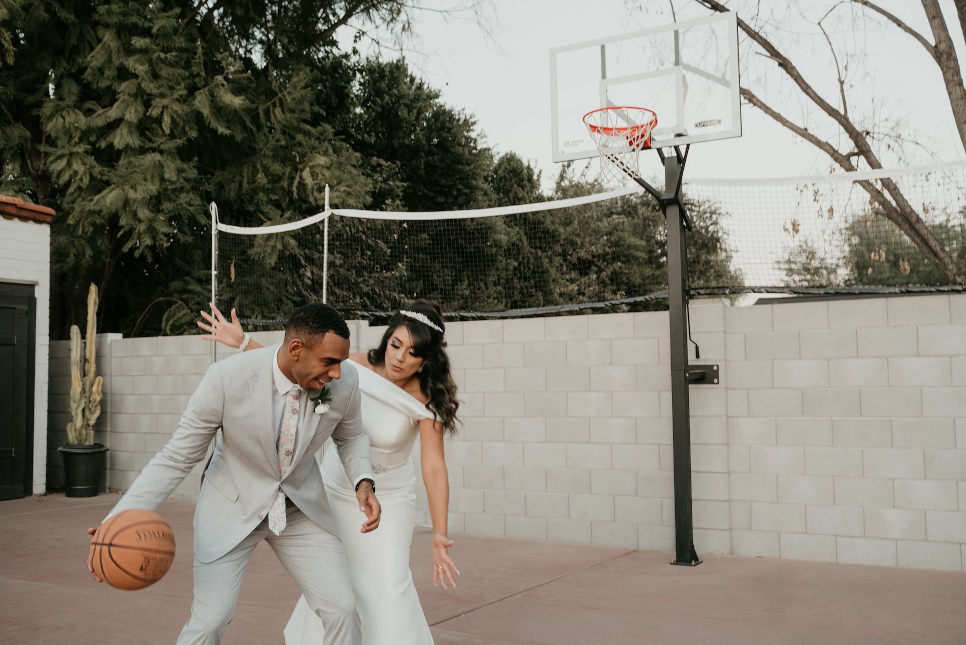 A bride and groom are playing basketball on a court.