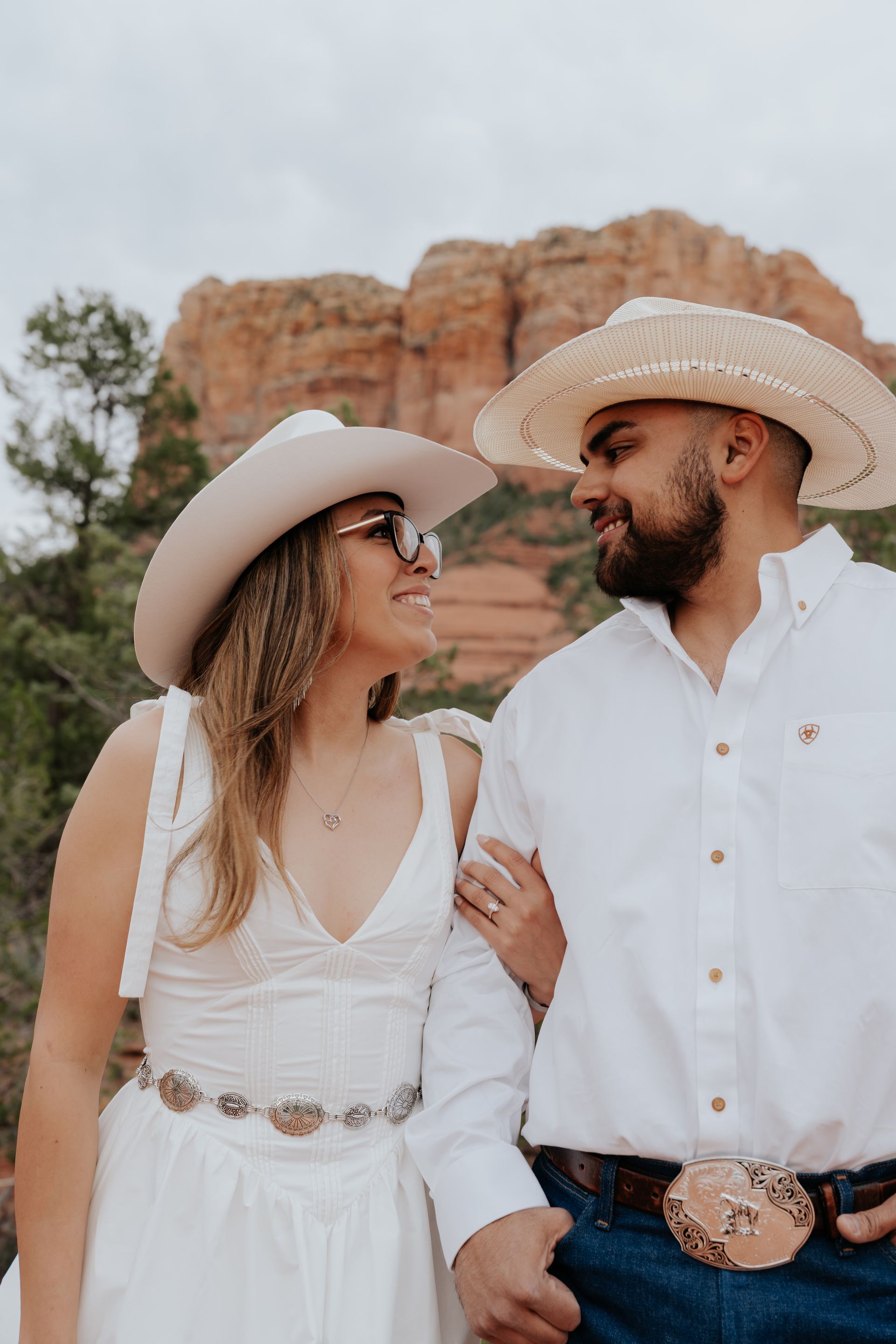 A man and a woman are standing next to each other wearing cowboy hats and sunglasses.