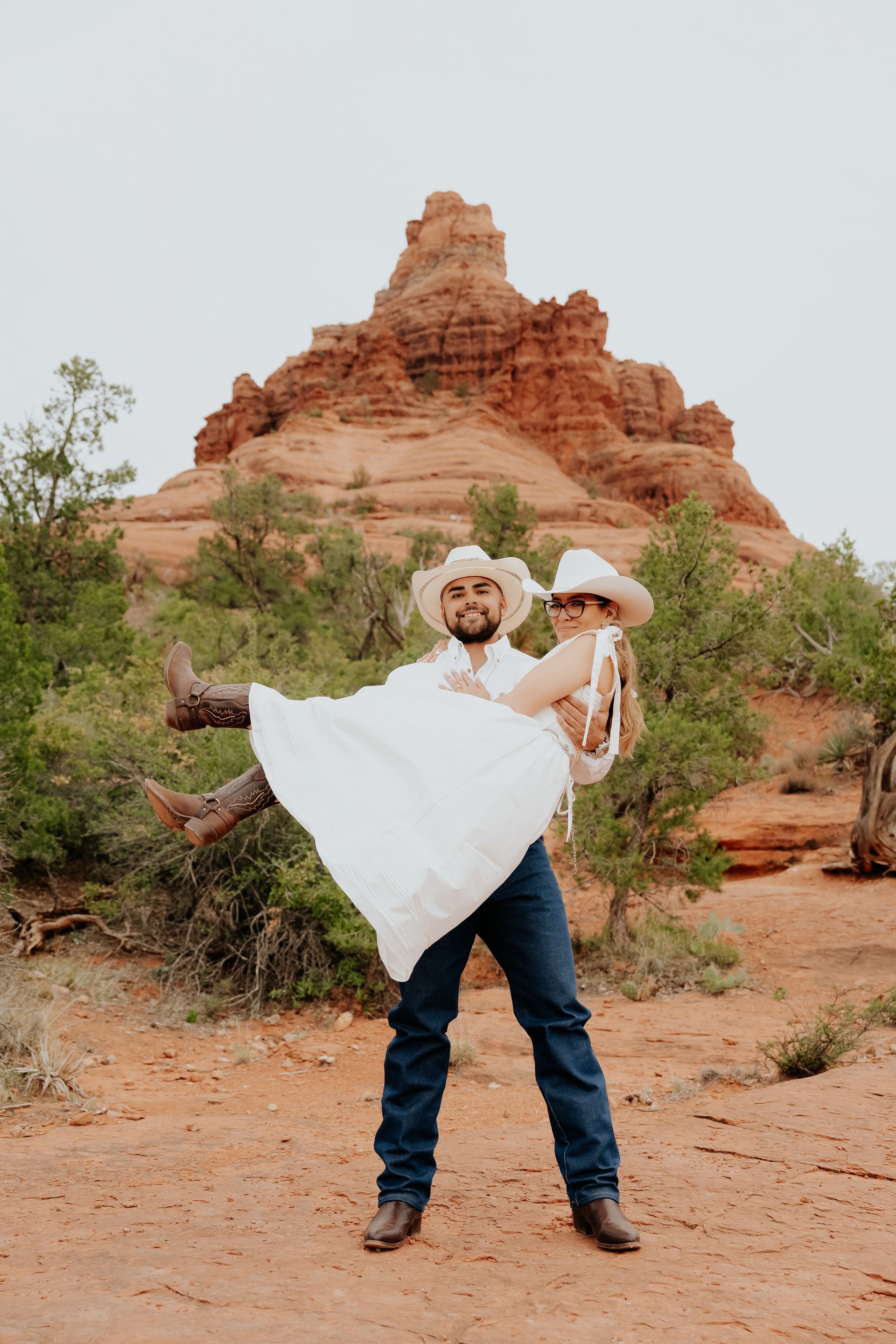A man is holding a woman in his arms in front of a mountain.