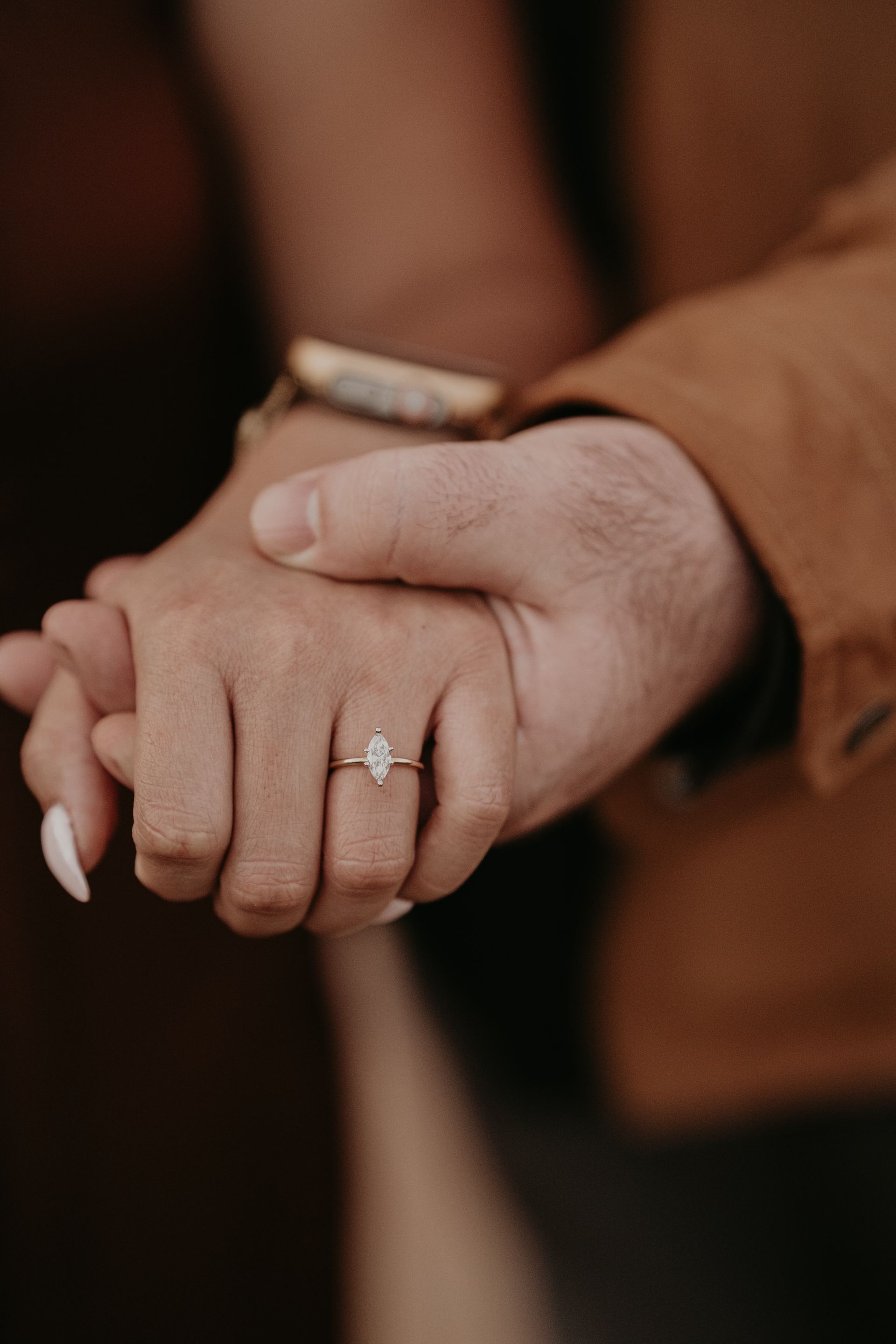 A close up of a person holding another person 's hand with a ring on their finger.