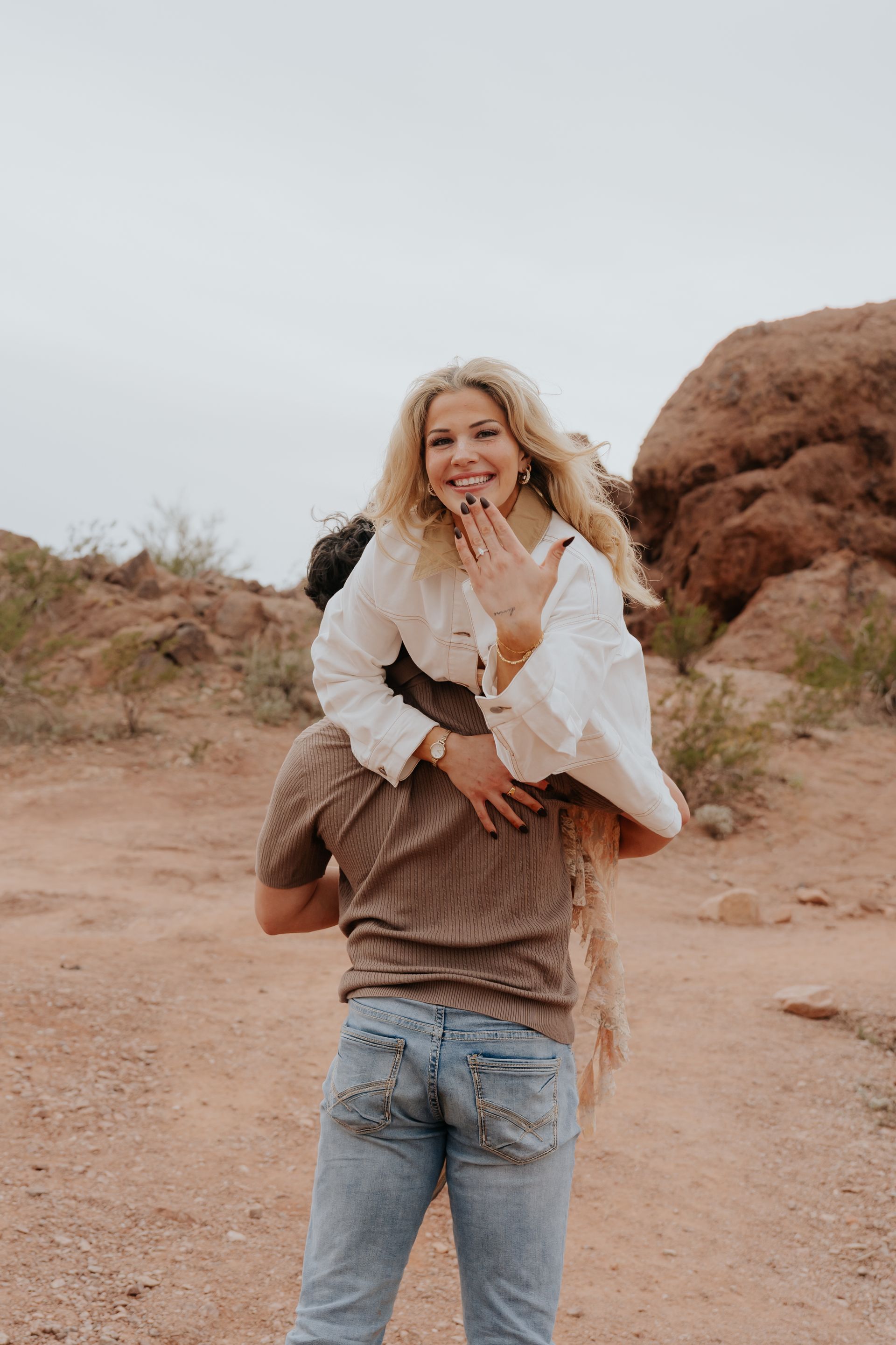 A man and a woman are holding hands in the desert.