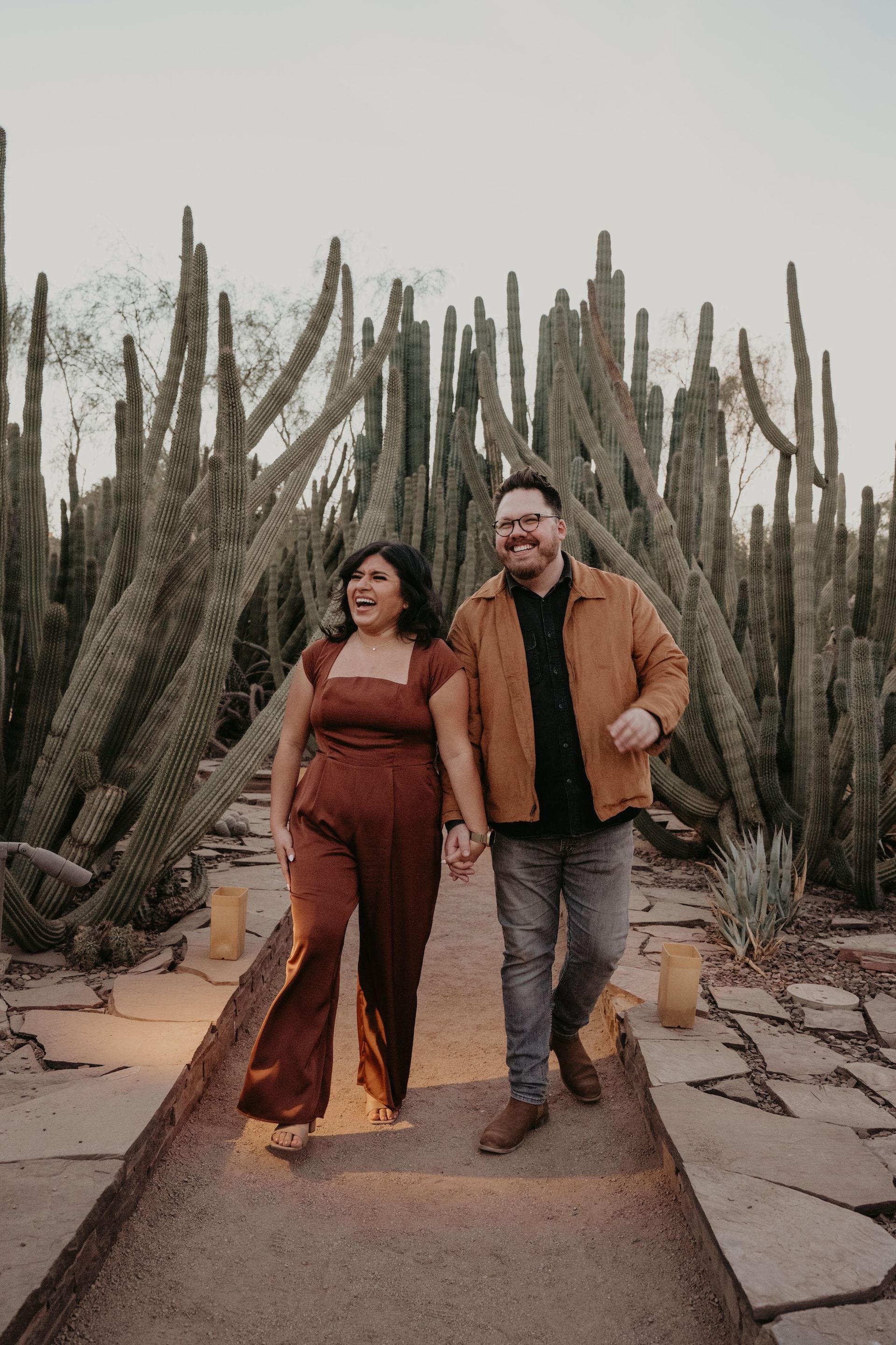 A man and a woman are walking down a path holding hands.