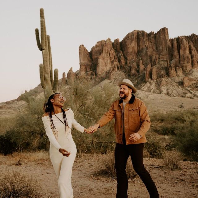 A man and a woman are holding hands in the desert.