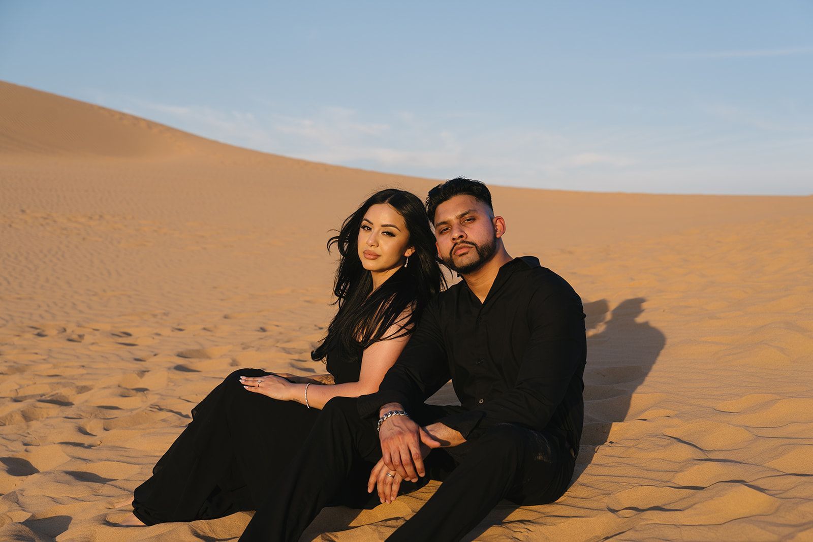 A man and a woman are holding hands in the desert.