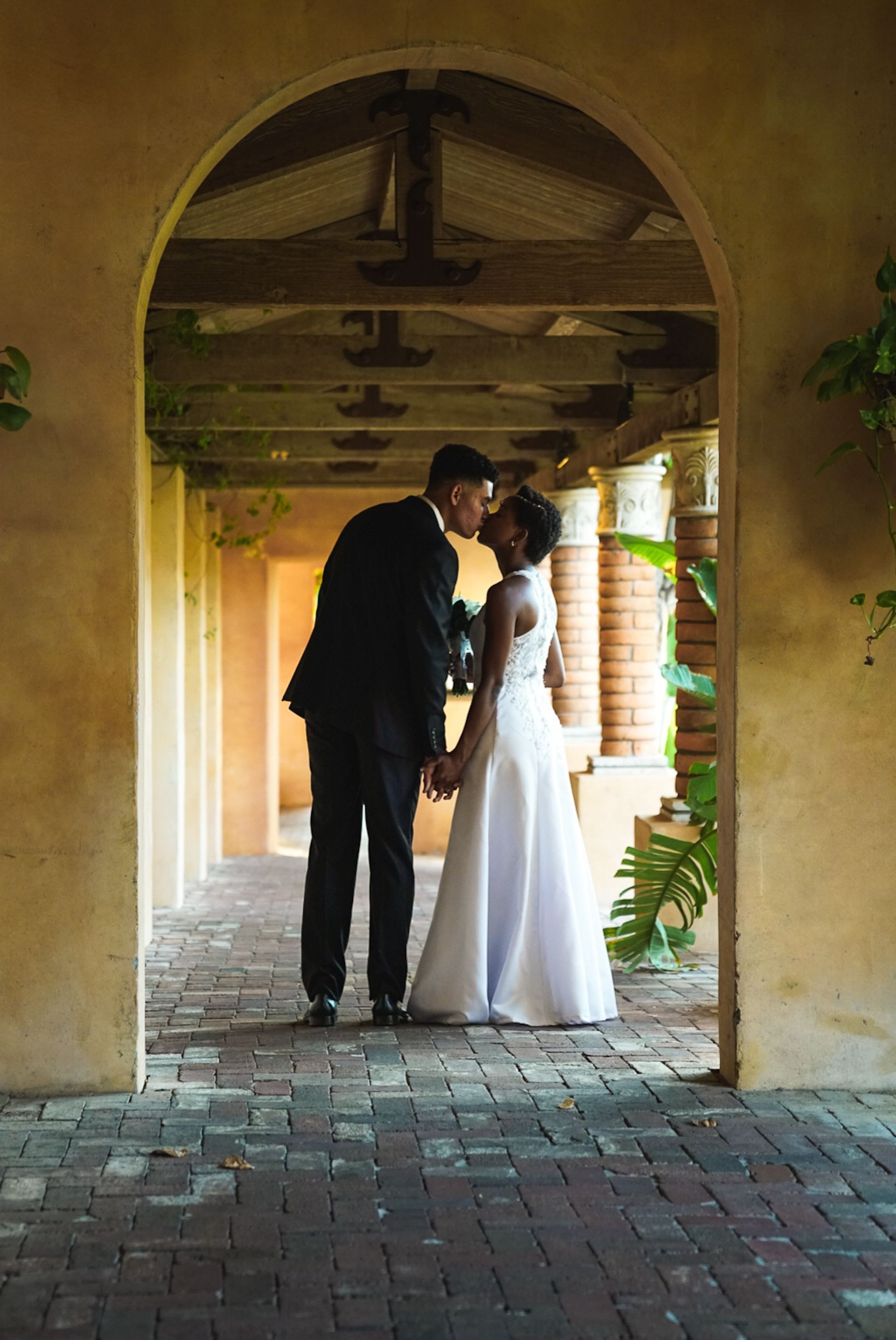 A bride and groom are kissing under an archway.