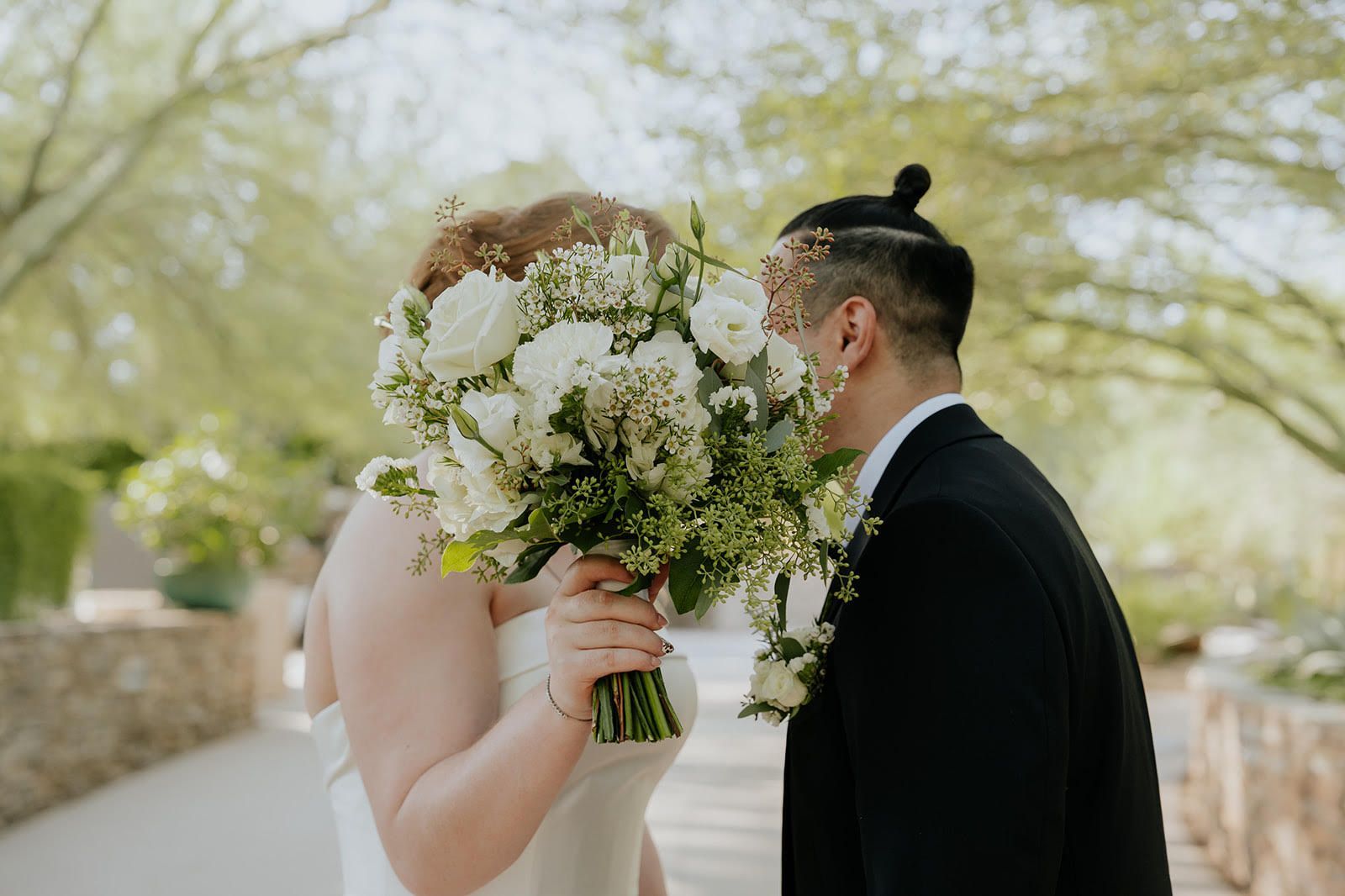 Bride and groom sharing a romantic kiss during their wedding dance at night under string lights.