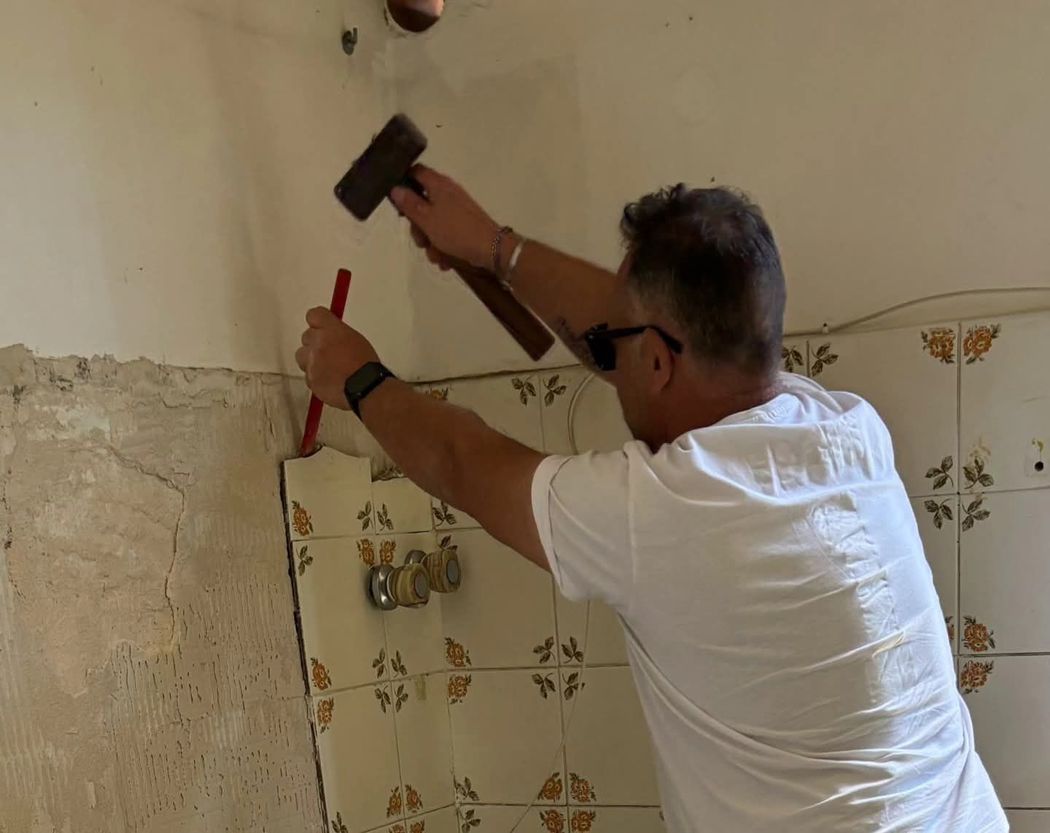Un uomo sta lavorando su un muro con un martello