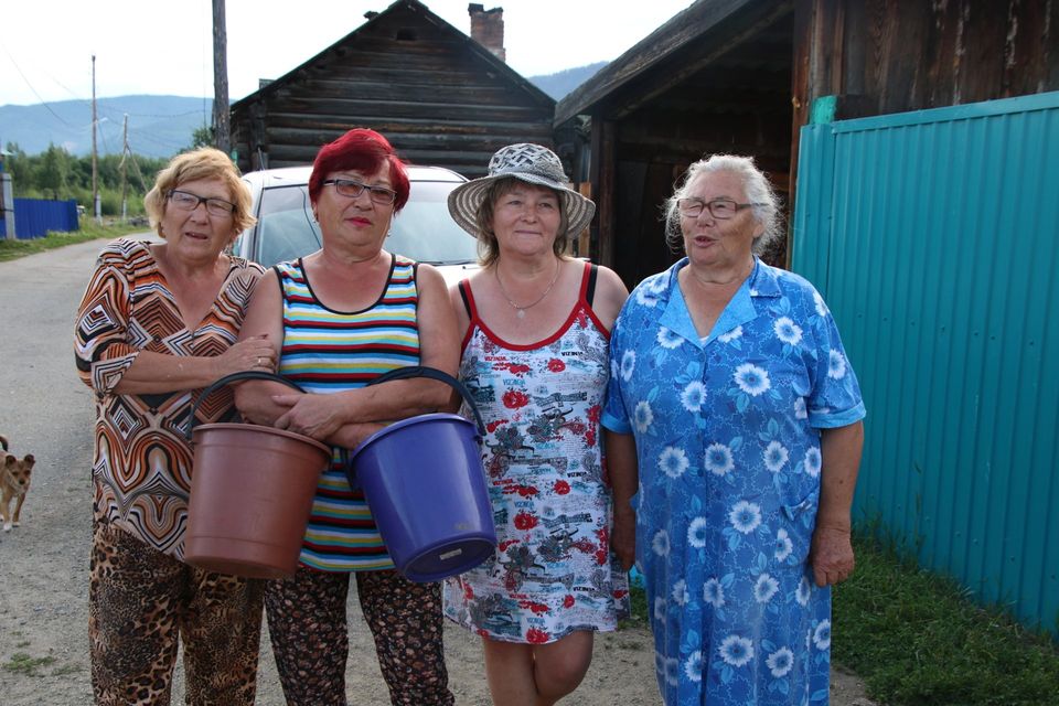 vier Russische vrouwen in schort met emmers in de hand in Siberie