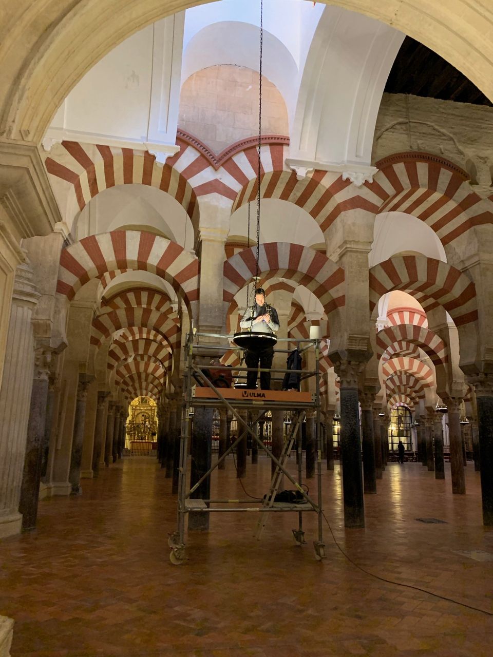 Man repareert lamp in de mezquita in cordoba