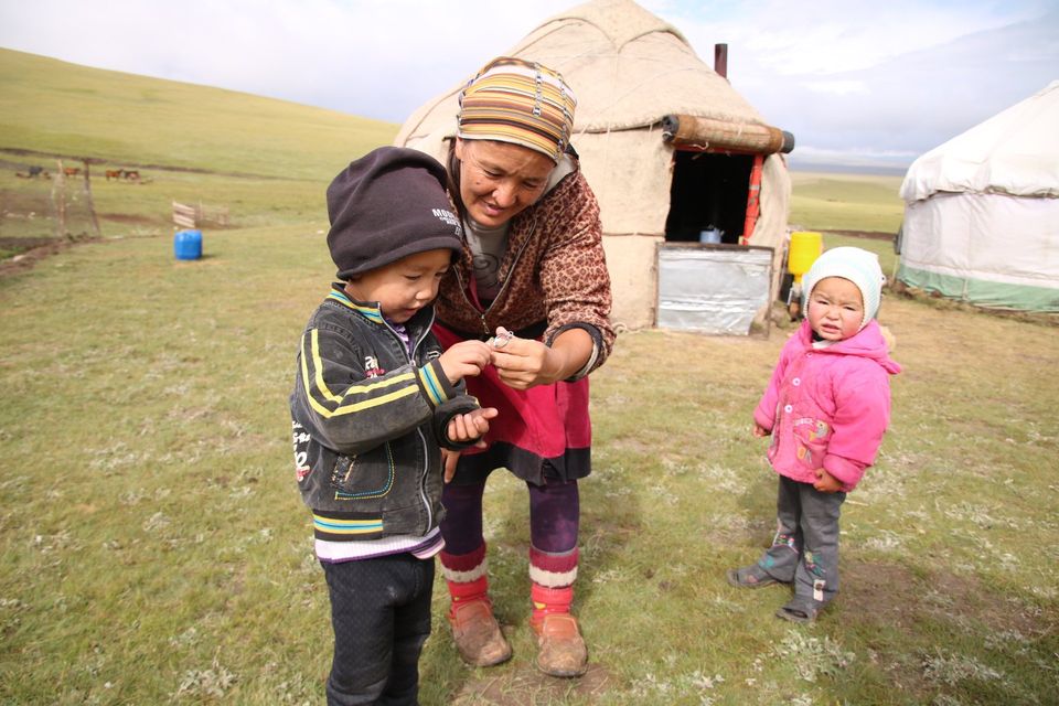 moeder met twee kinderen voor een yurt op hoogvlakte Kirgizië