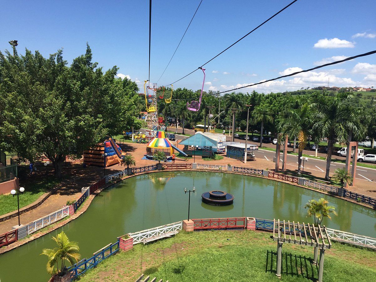 Um teleférico está passando sobre um lago em um parque. Hotel Barra Bonita