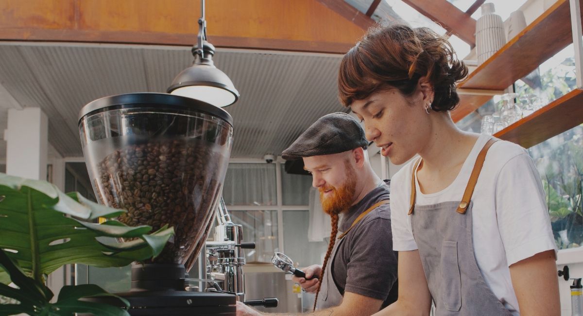 Two cafe workers making coffee