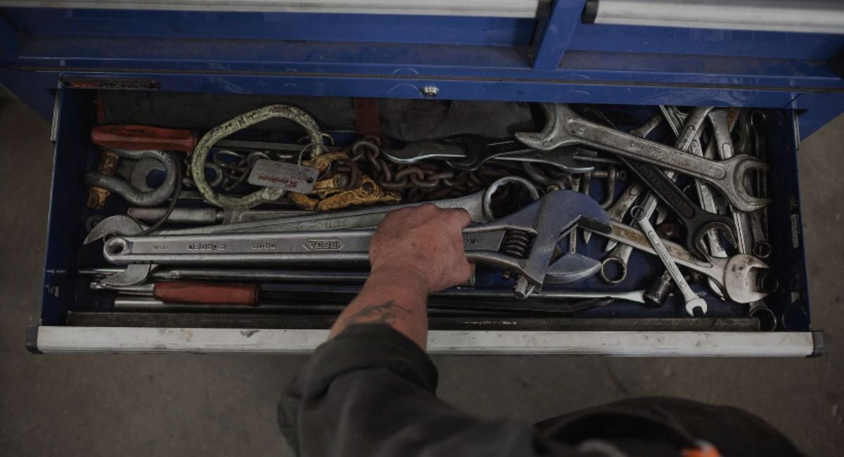 A person is reaching into a drawer filled with tools.