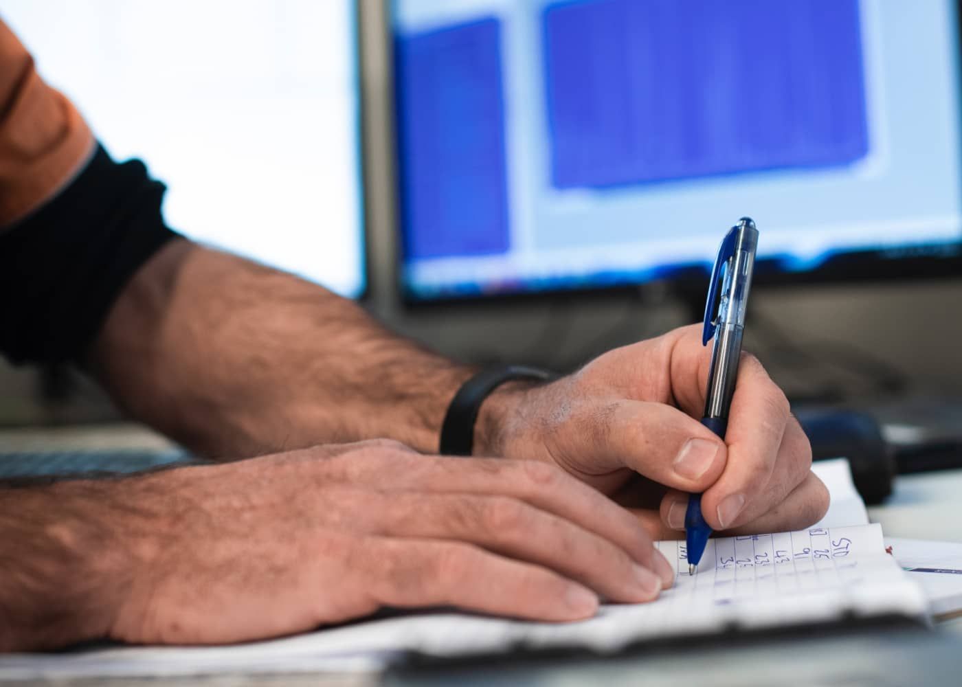 A man is writing on a piece of paper with a pen.