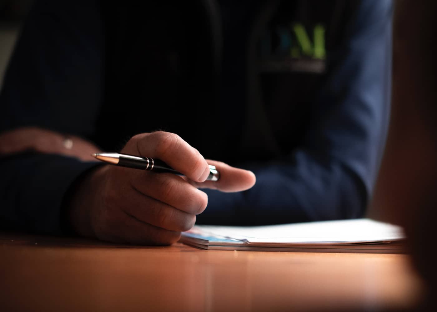 A person is sitting at a table holding a pen in their hand.