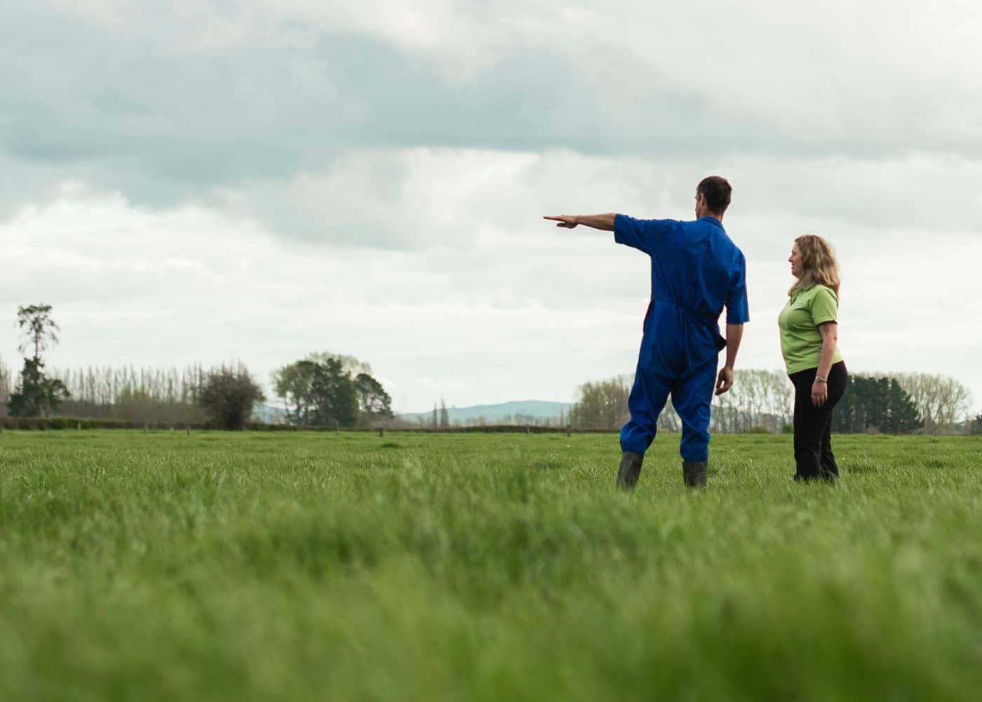 A man and a woman are standing in a grassy field.