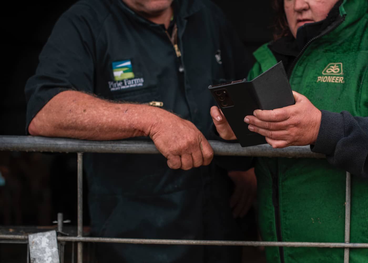 Two men are standing next to each other looking at a cell phone.