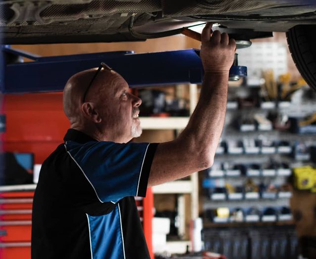 A man is working under a car in a garage