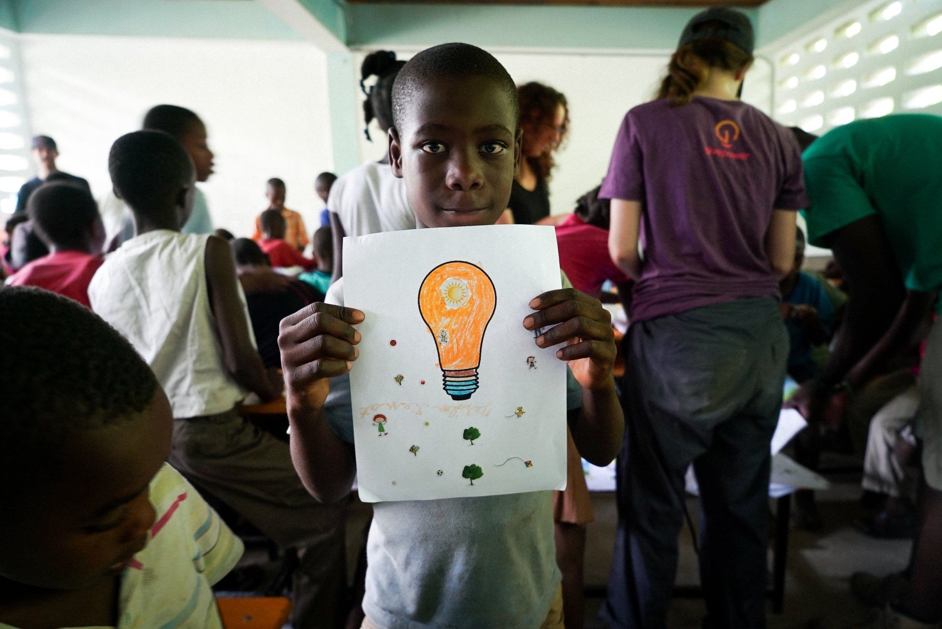 En ung pojke håller upp en teckning av en glödlampa.