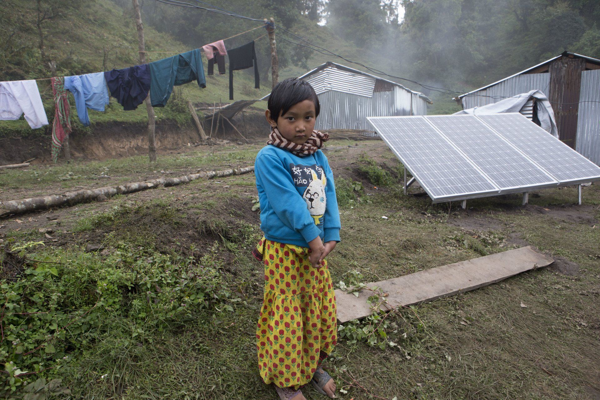 En liten flicka står framför en solpanel.
